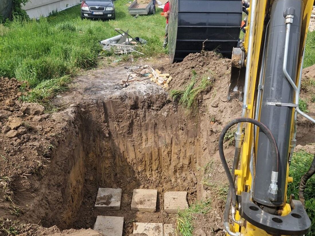 Vykopaná jama pre žumpu s betónovým podkladom medzi rodinnými domami